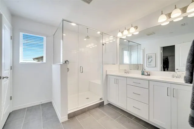 a bathroom with a double vanity sink mirror and shower