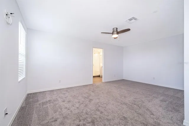 an empty room with a window and a ceiling fan