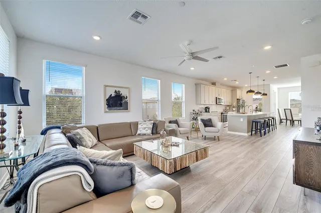 a living room with furniture kitchen view and a large window