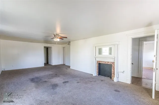 an empty room with windows and fireplace