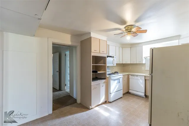 a kitchen with stainless steel appliances a refrigerator a sink dishwasher a stove and white cabinets with wooden floor