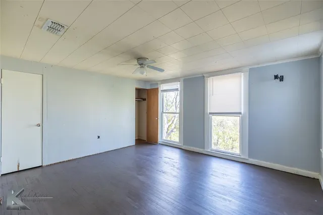 a view of an empty room with a window and wooden floor