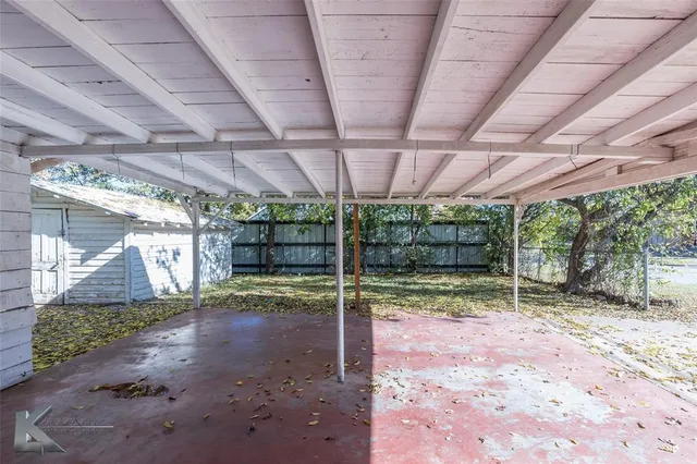a view of a backyard with wooden fence and a porch