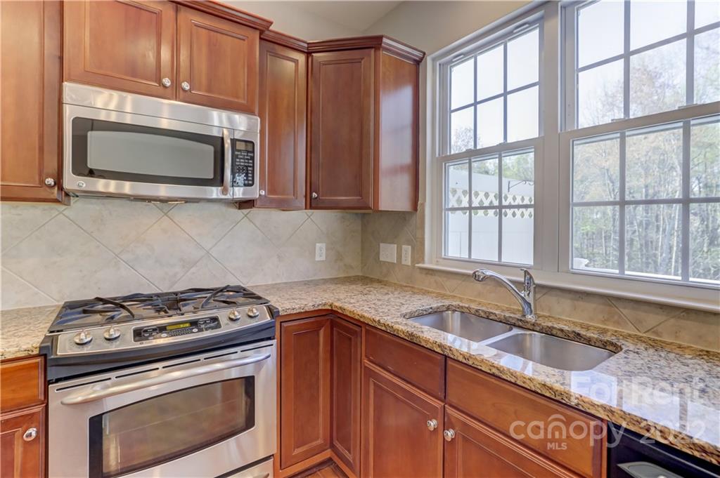 562 6th Baxter Crossing Fort Mill, SC 29708 - Photo 12 of 48 a kitchen with granite countertop a stove a sink and a microwave