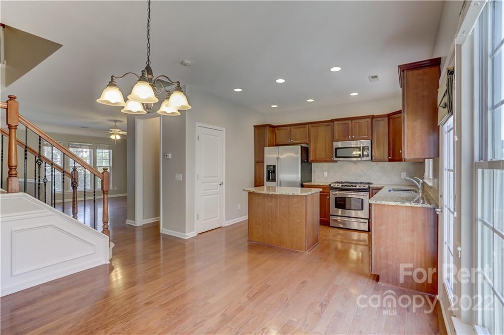 562 6th Baxter Crossing Fort Mill, SC 29708 - Photo 15 of 48 a kitchen with stainless steel appliances granite countertop a refrigerator a stove top oven a sink dishwasher and a refrigerator with wooden floor