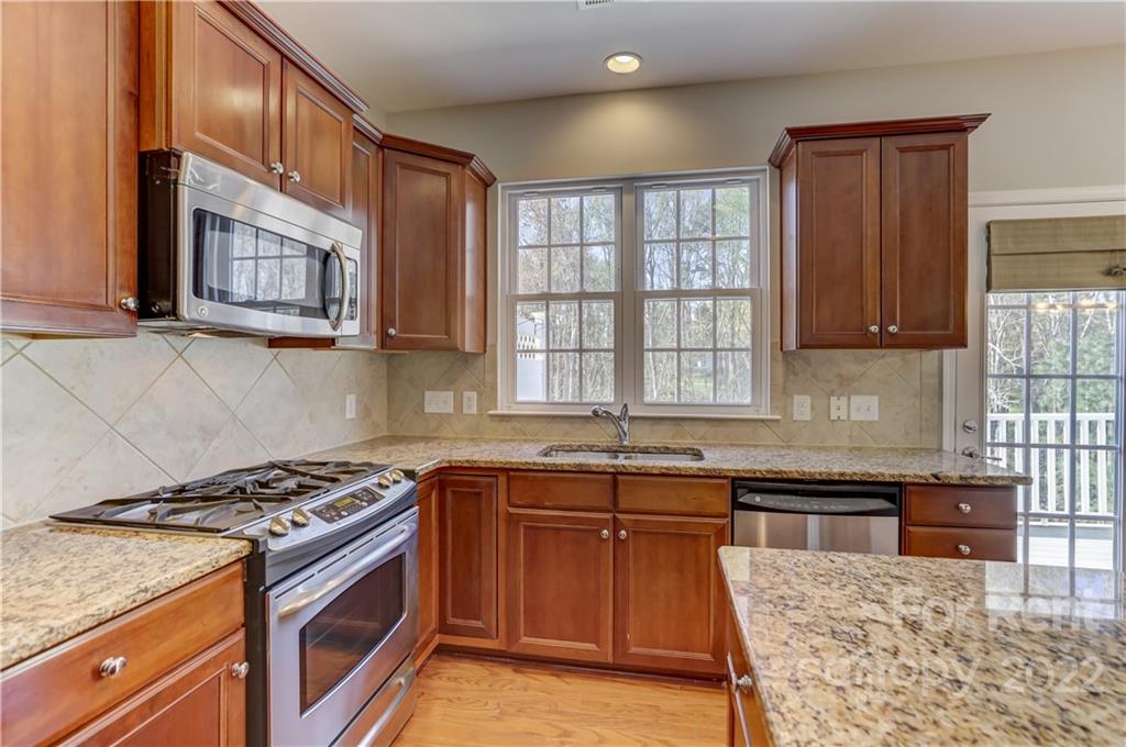 562 6th Baxter Crossing Fort Mill, SC 29708 - Photo 10 of 48 a kitchen with stainless steel appliances granite countertop a stove a sink dishwasher and cabinets with wooden floor