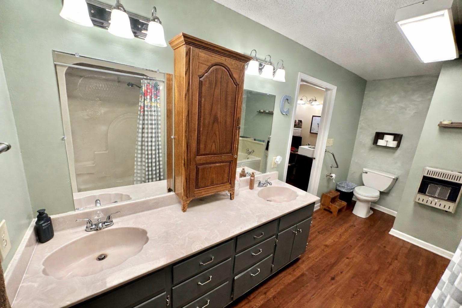1347 Becton William Road Ripley, TN 38063 - Photo 24 of 24 Bathroom featuring double vanity, heating unit, a textured ceiling, dark wood-style flooring, and curtained shower