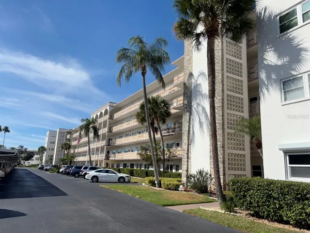 front view of a building with a street and palm trees