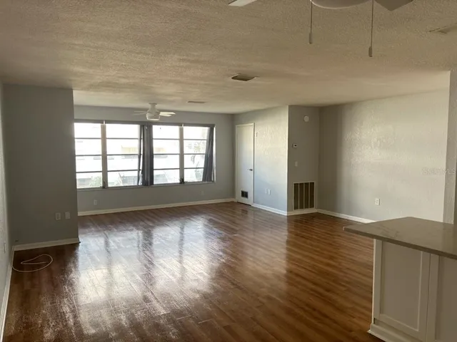 a view of kitchen and empty room with wooden floor