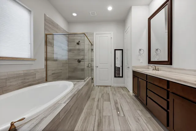 a spacious bathroom with a tub a sink and mirror