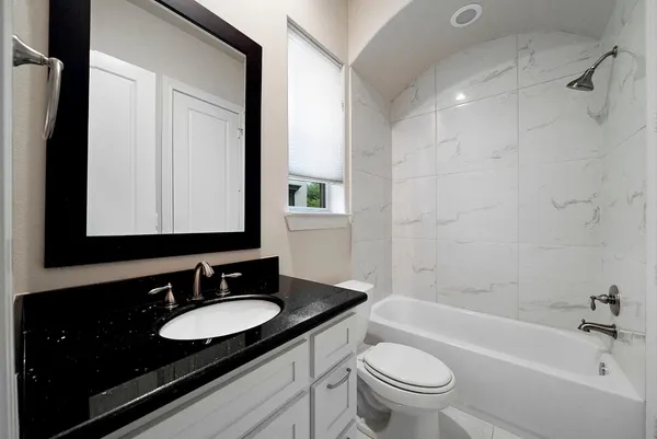 a bathroom with a granite countertop sink toilet and shower