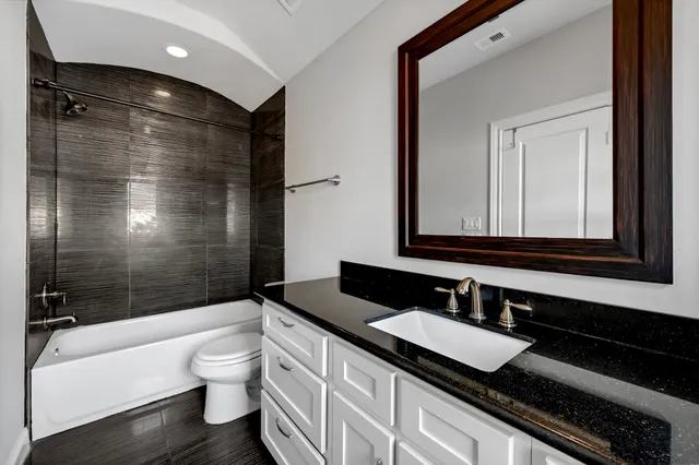 a bathroom with a granite countertop sink toilet and shower