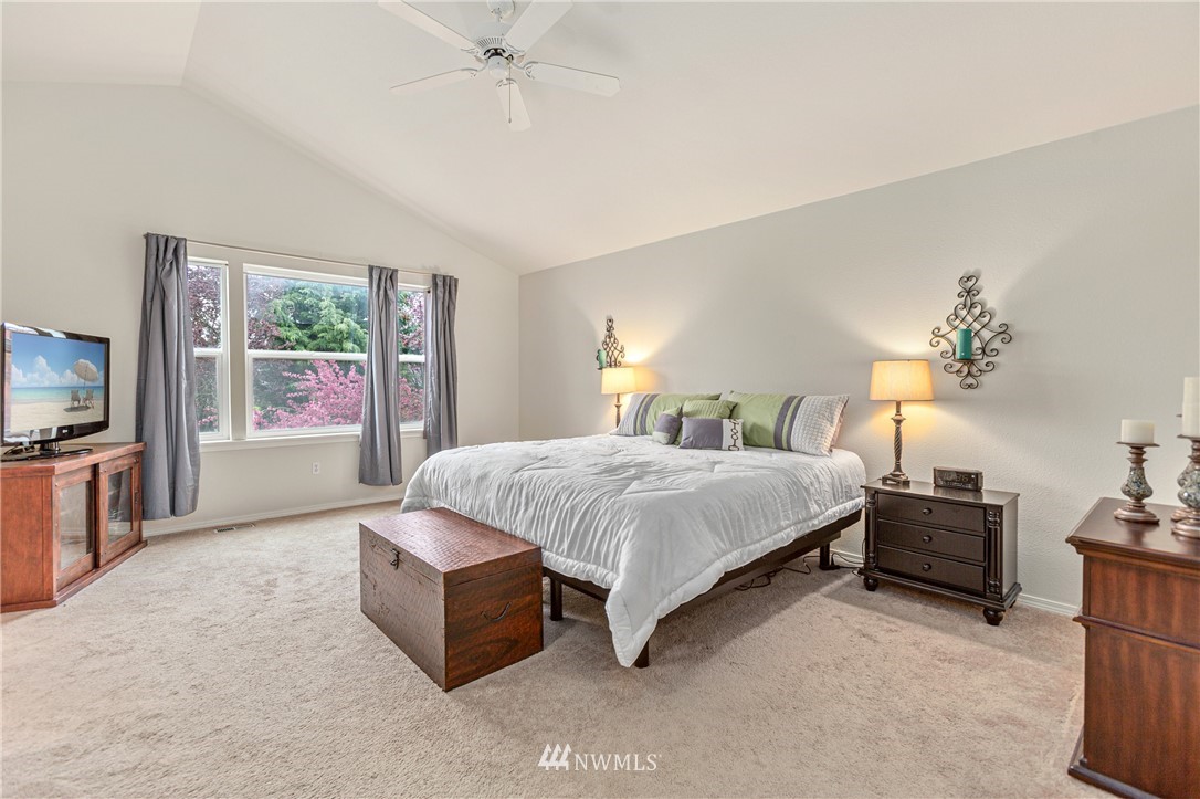 4313 147th Place Southeast Bothell, WA 98012 - Photo 18 of 29 a spacious bedroom with a bed a mirror on dresser and a chandelier