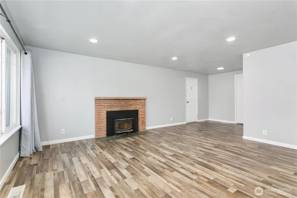 a view of empty room with wooden floor and fireplace