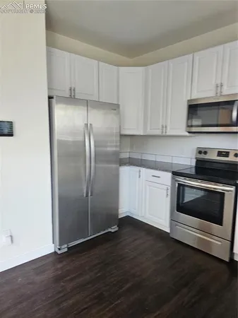 a kitchen with granite countertop white cabinets and appliances