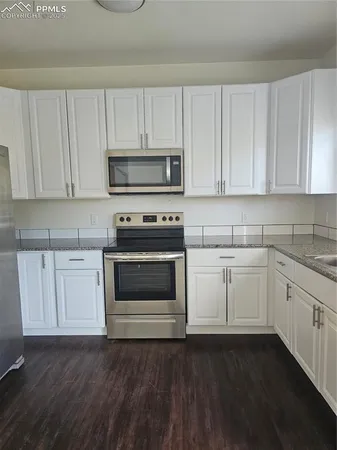 a kitchen with granite countertop white cabinets sink and window