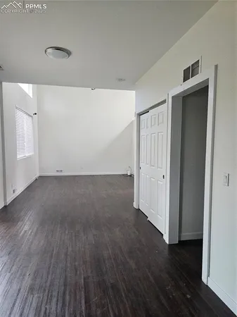 an empty room with wooden floor and closet area