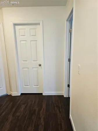 a view of a hallway with wooden floor and a bathroom