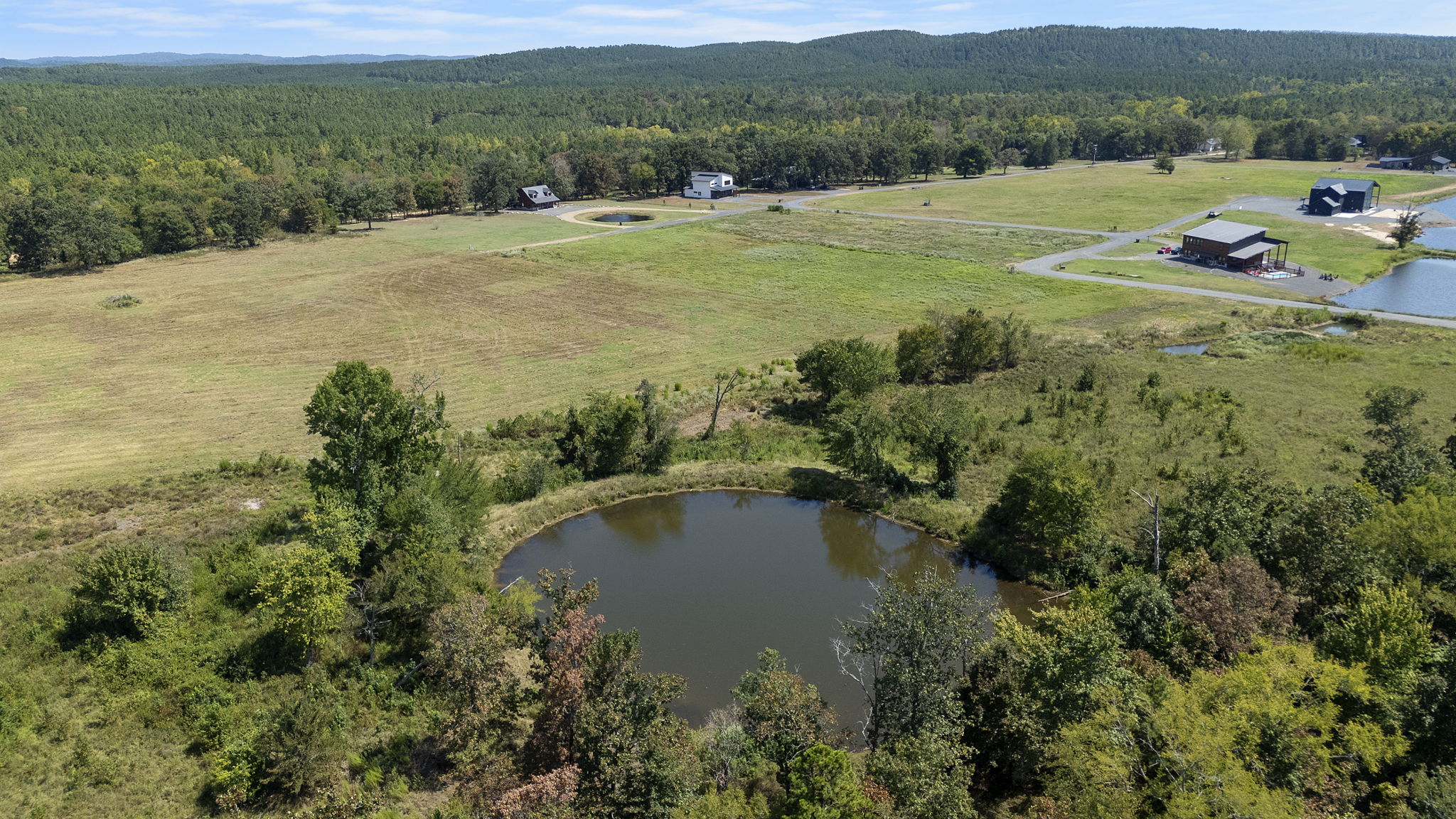 0 Rutty Pne Ridge Broken Bow, OK 74728 - Photo 1 of 22 Expansive property featuring a circular pond, open grassy areas, and dense natural tree lines