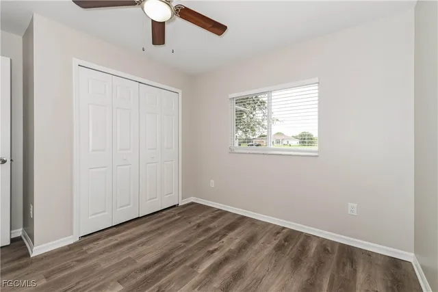 an empty room with wooden floor cabinet and windows