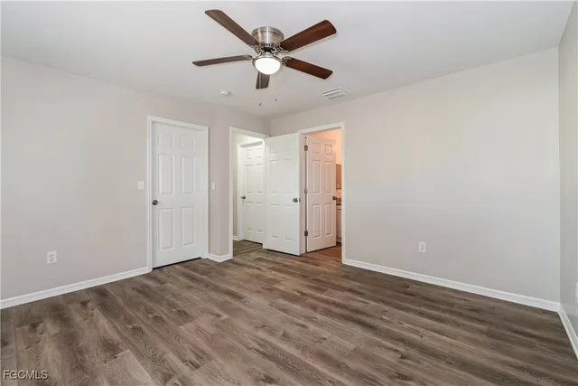 an empty room with wooden floor and ceiling fan