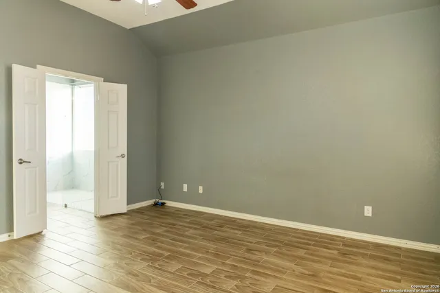 an empty room with wooden floor and windows