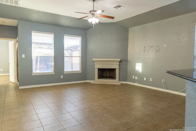 an empty room with windows and fireplace