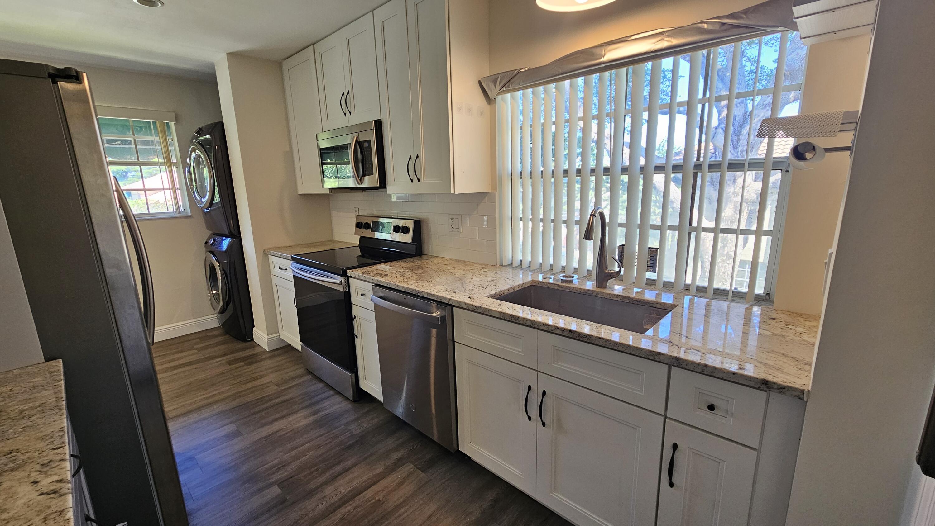 a kitchen with stainless steel appliances granite countertop a stove a sink and a refrigerator with wooden floors