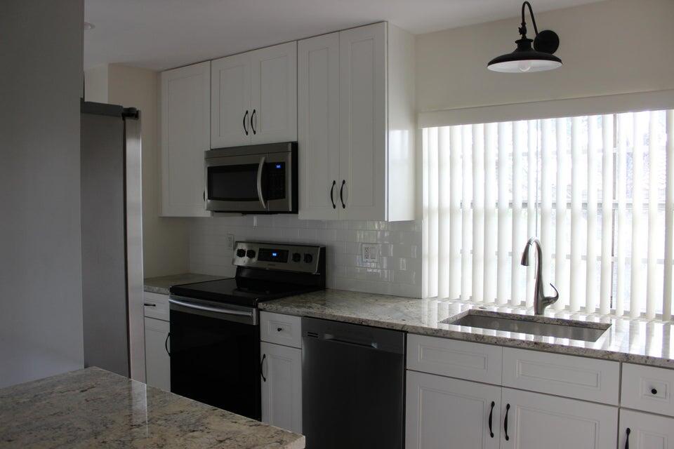 6560 Via Regina Boca Raton, FL 33433 - Photo 8 of 15 a kitchen with granite countertop a stove a sink and a microwave