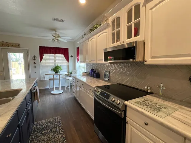 a kitchen with stainless steel appliances kitchen island granite countertop a stove a sink and a microwave