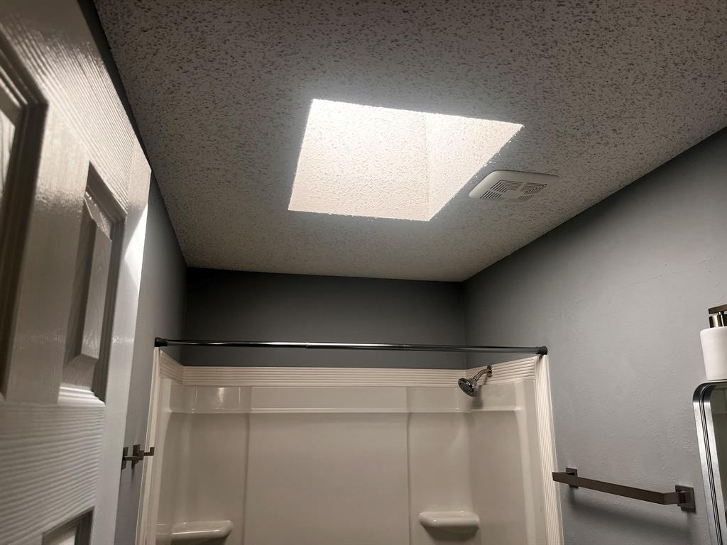 1007 Mack Place Denton, TX 76209 - Photo 36 of 37 Bathroom featuring a skylight, a textured ceiling, and a shower