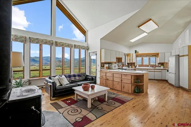 a living room with kitchen view and large windows