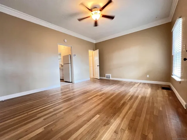 an empty room with wooden floor and windows