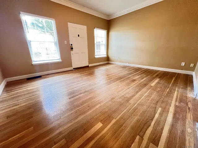 a view of an empty room with wooden floor and a window