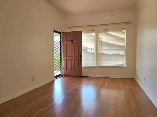 a view of an empty room with wooden floor and a window