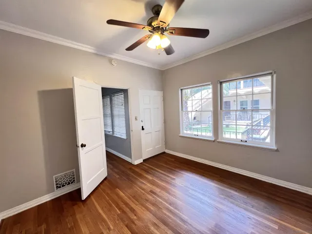 a view of an empty room with window hardwood floor and a ceiling fan