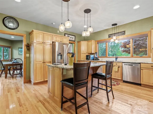 a kitchen with stainless steel appliances a dining table chairs stove and refrigerator