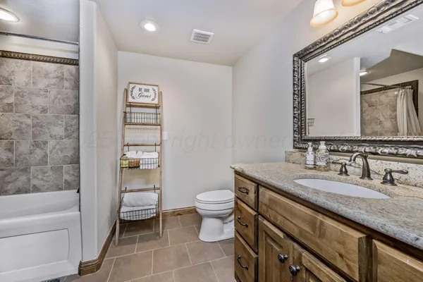 a bathroom with a granite countertop sink a toilet a mirror and shower