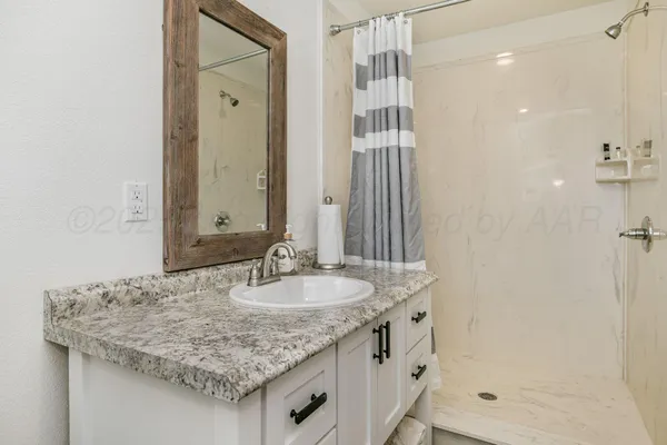 a bathroom with a granite countertop sink and a mirror