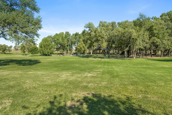 a big yard with lots of green space and trees in the background