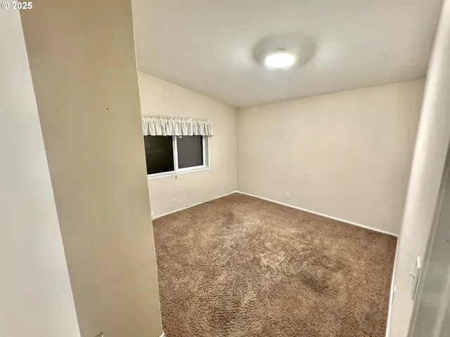 an empty room with a ceiling fan and window