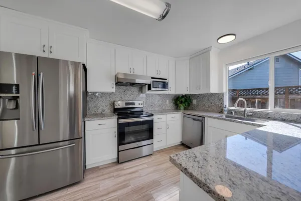 a kitchen with granite countertop a refrigerator stove and sink