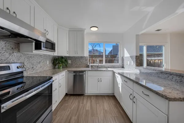 a kitchen with granite countertop a sink stainless steel appliances and cabinets