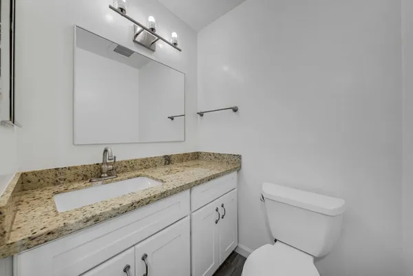 a bathroom with a granite countertop sink a toilet and a mirror