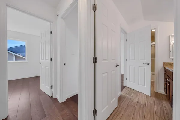 a view of a hallway with wooden floor and a bathroom