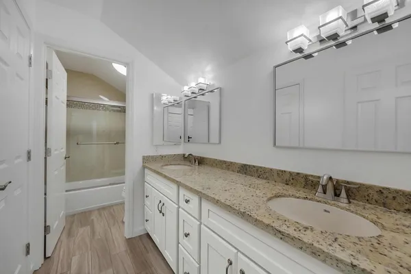 a bathroom with a granite countertop double vanity sink and mirror