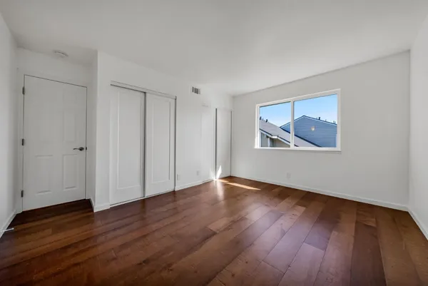 a view of an empty room with wooden floor and a window