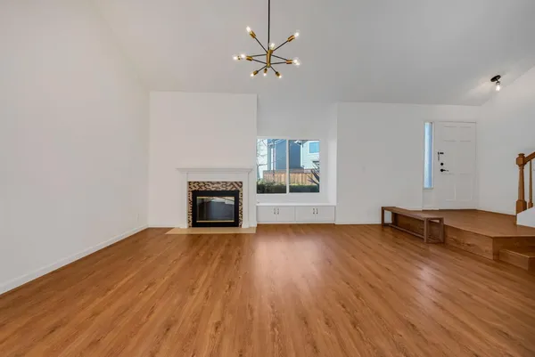 a view of a room with wooden floor a ceiling fan a fireplace and windows