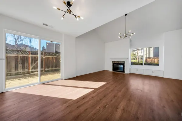 a view of an empty room with window and wooden floor