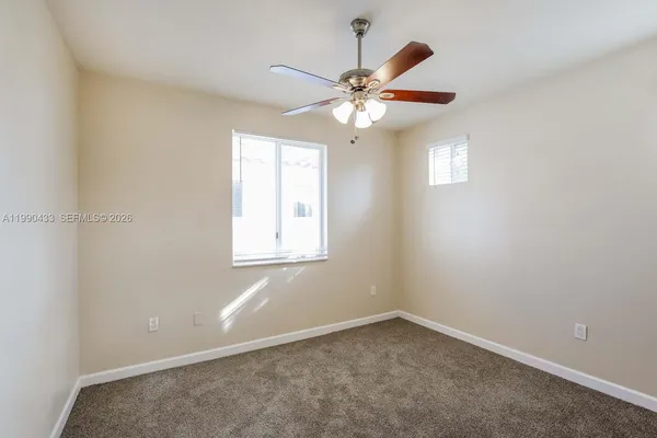 an empty room with windows and fan